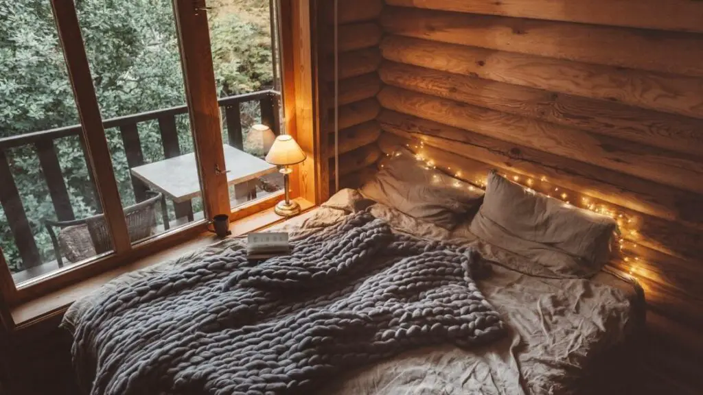 The use of fairy lights behind the bed gives this room a romantic, almost magical feel.  The log walls and large window looking over the forest add to this natural look.
