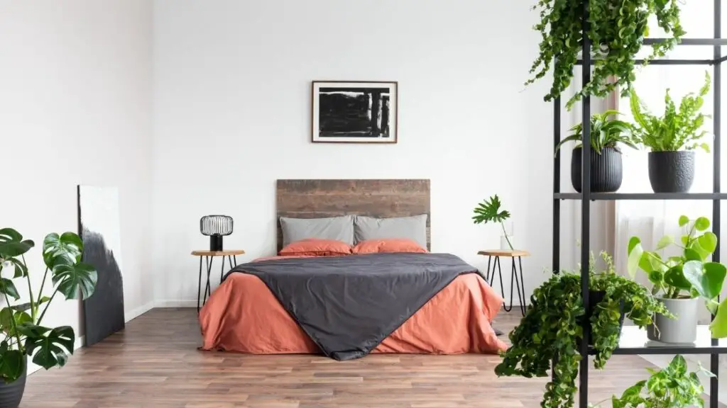 The many plants give this room an airy, spacious feel, while still being warm and inviting.  The headboard and the floor use wood to add to the rustic theme.
